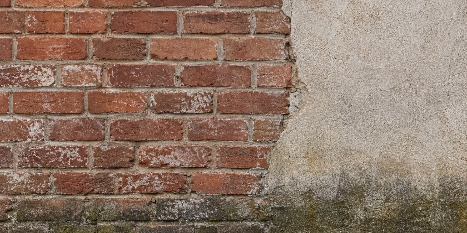 Fragment starej elewacji z cegły i tynku mineralnego z delikatnym śladem zawilgocenia