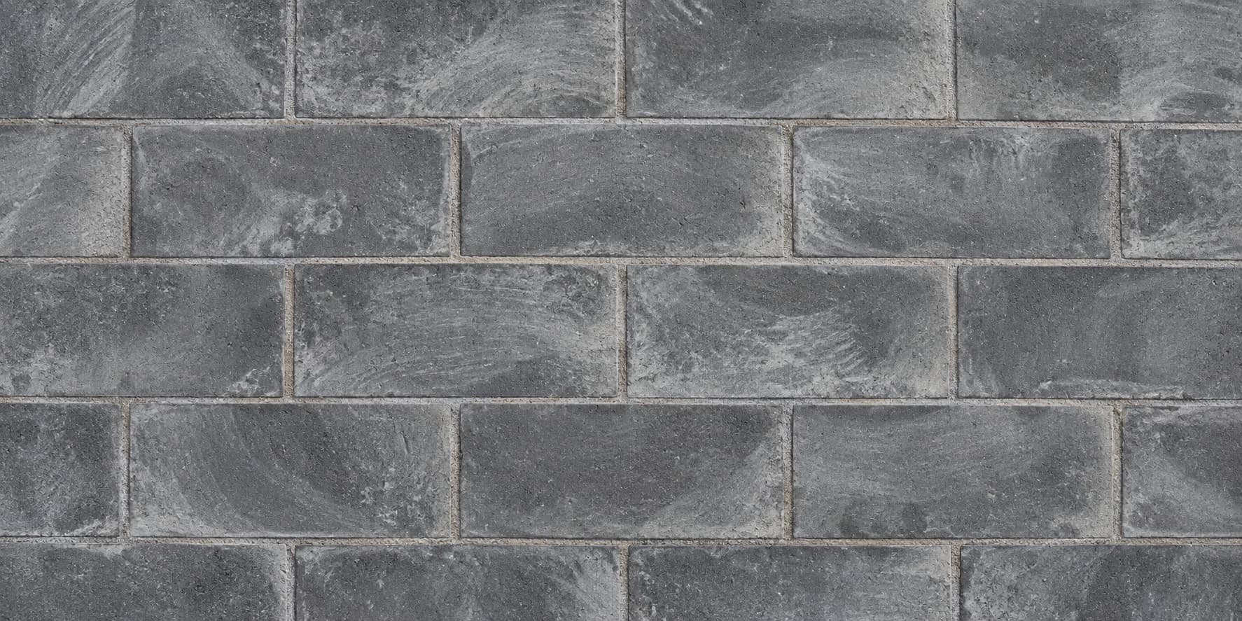Anthracite block paving covered in streaks of whitish-grey cement haze